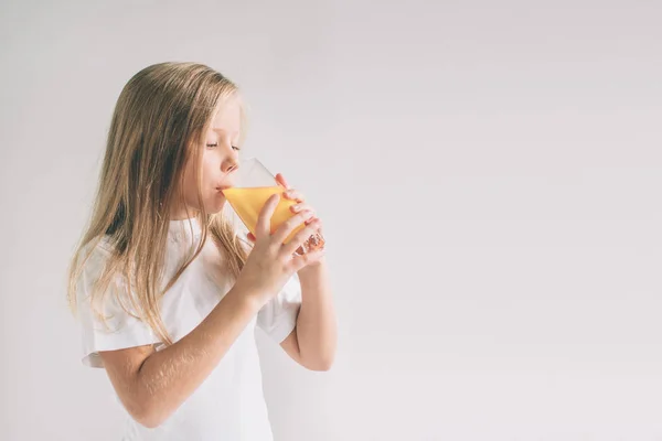 Szczęśliwa dziewczyna trzymając szklankę soku pomarańczowego na białym tle. Frajerem jest noszenie okularów — Zdjęcie stockowe