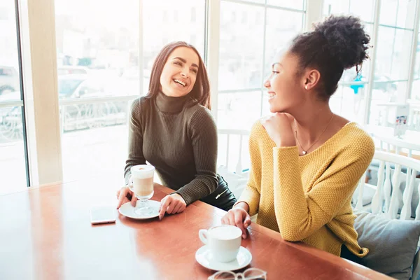 Zwei beste Freundinnen sitzen im Café und verbringen gute Zeit miteinander. Mädchen trinken etwas Latte und genießen ihre Unterhaltung. Nahaufnahme. — Stockfoto