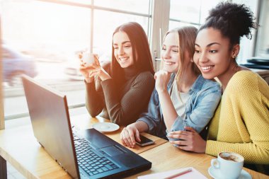 Üç gourgeous arkadaşlarım kafede vardır. Onlar vlose için geçerli bir dizüstü bilgisayar ve dizüstü ekran ve biriyle konuşurken aynı anda sohbet ar için loking oturuyorlar