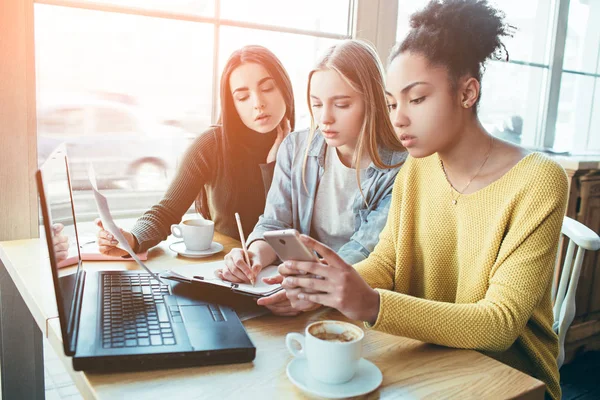 Nahaufnahme und Schnitt von drei Mädchen, die zusammen sitzen und das Diagramm des Geldeinkommens studieren. Sie wollen analysieren, wie viel Geld sie bekommen haben und wie viel sie in Zukunft verdienen werden. — Stockfoto