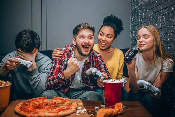 Adorable and emotional picture of a guy who has just won the game. He is happy about that and girls are greeting him. But his friend has lost and so sad about that. — Stock Photo, Image