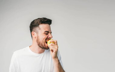 Adam belgili tanımlık fotoğraf çerçevelemek sol tarafında duran ve bir elma ısırma. Kıpır kıpır durduramazsın ekşi bir meyvedir. Kesme görünümü.