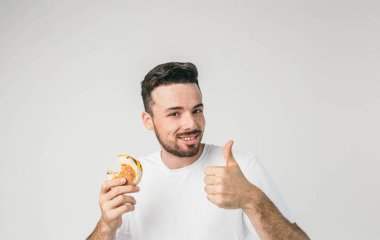 Harika ve çekici stading duvar ve sol eliyle büyük başparmak gösterilmesini ve burger bir parça sağ elinde tutan biri. Burger tadı hoşuma gitti.