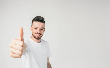 Kamerayı düz seyir ve büyük baş parmağını o kadar gösterilen bir çerçevenin sol tarafında duran bir adam. O neşeli ve mutlu görünüyor.