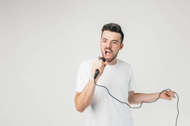 Bir mikrofon sağ el ve sol elinde bir kablo tutarak ve yüksek sesle ve çok emin şarkı beyaz t-shirt giyen başka bir resmi. Şarkı inanılmaz emin.