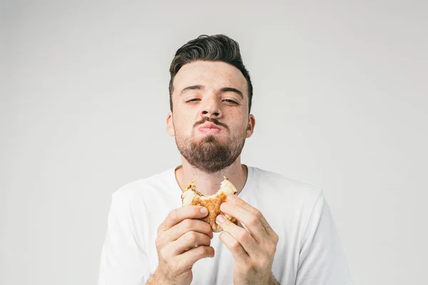 Zblízka se muže jíst hamburger. On se těší proces chutná. Nebylo mu to jíst po dlouhou dobu. Písma. — Stock fotografie