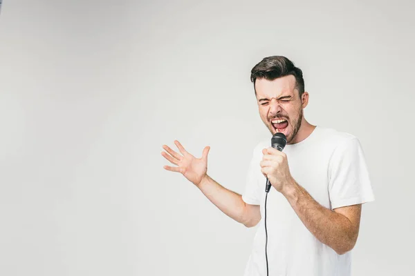 Nice picture of an emotional guy singing in microphone. His trying to do his best and reaches the highest note in the song. Cut view. — Stock Photo, Image