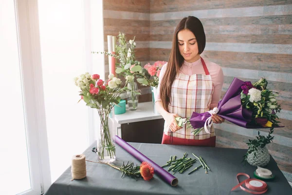 Floristin bei der Arbeit: hübsche junge dunkelhaarige Frau, die einen modernen Strauß aus verschiedenen Blumen herstellt. Frauen arbeiten in Werkstatt mit Blumen — Stockfoto