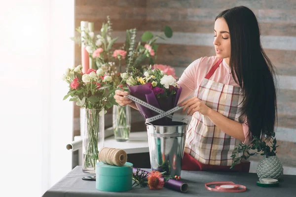 Florista femenina en el trabajo: mujer morena bastante joven haciendo ramo moderno de moda de diferentes flores. Mujeres trabajando con flores en taller — Foto de Stock