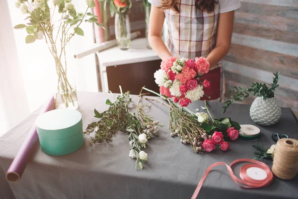 Florista femenina en el trabajo: mujer morena bastante joven haciendo ramo moderno de moda de diferentes flores. Mujeres trabajando con flores en taller — Foto de Stock