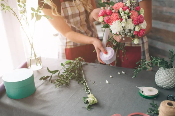 Flores entrega vista superior. Floristas creando orden, haciendo ramo de rosas en la tienda de flores. Dos floristas femeninas están haciendo ramos. Una mujer recogiendo rosas para un montón, otra chica está trabajando también . — Foto de Stock