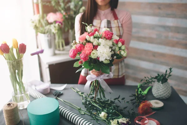 Florista femenina en el trabajo: mujer morena bastante joven haciendo ramo moderno de moda de diferentes flores. Mujeres trabajando con flores en taller — Foto de Stock