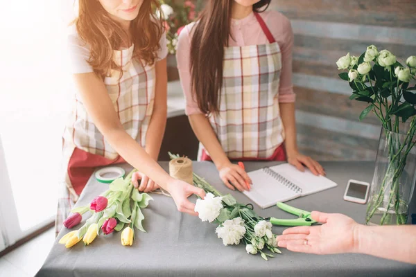 Flores entrega vista superior. Floristas creando orden, haciendo ramo de rosas en la tienda de flores. Dos floristas femeninas están haciendo ramos. Y un cliente que pide flores ramo floristería — Foto de Stock