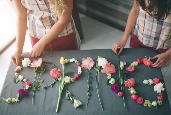 Flores entrega vista superior. Floristas creatin palabra SPRING hecha de flores en el fondo. Concepto de primavera. Puesta plana — Foto de Stock