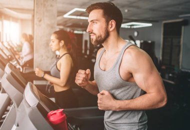 Koþmak üstünde çalışan makine iki kaslı insanların kapatın. Onlar exerecising çok zor vardır. Kesme görünümü.