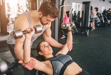 Daha güçlü ve daha iyi almak için kız arkadaşı yardım birini kapatın. Onu dumbells ile egzersiz ile desteklemektedir. Kesme görünümü.