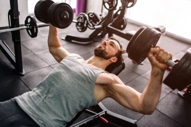 Güçlü bir adamın itme yapıyor yakın ups ile dumbells. Consentrated sadece bu egzersiz yapmak ve başka hiçbir şey üzerinde o. Kesme görünümü.