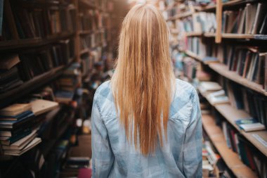 Bookshelfs ile yeni ve olb kitaplar arasında bir resim og kız. İşte bir karışıklık her yerde odaya. O IR bir araştırma yapma.