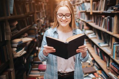 Parlak ve sıcak resim zeki öğrenci kitap okuma. Kız gülümseyerek ve daha fazla kitap okumaya devam etmek.