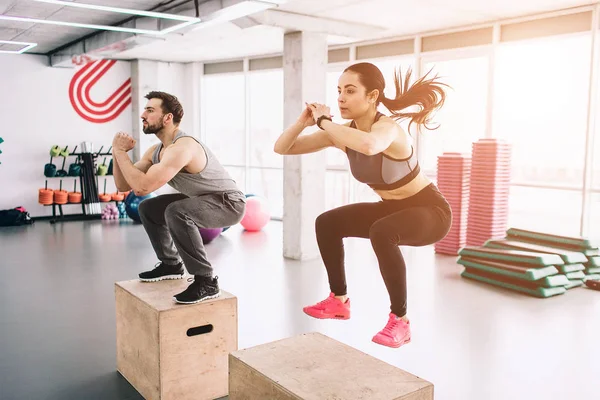 Een beeld van de slanke, goedgebouwde jonge man en vrouw doen springt op platform. Het is een harde oefening, maar ze doen het succesvol en met dilligence. — Stockfoto