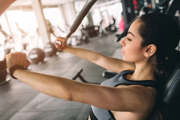 Uma foto de menina bonita fazendo os flexões na máquina. Ela é concentrada e séria. Fecha. Vista para corte . — Fotografia de Stock