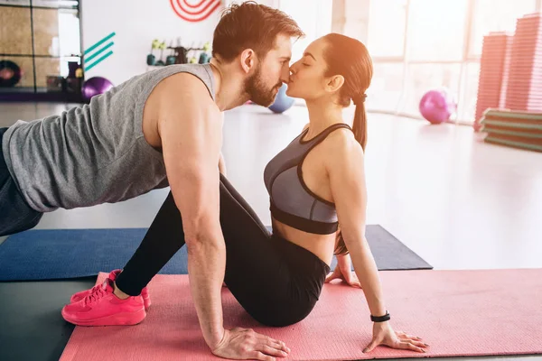 Gesneden beeld van een kerel die permanent in een hoge plank positie, terwijl zijn vriendin is hem zoenen. Het is zo tastbaar en ongelooflijke. — Stockfoto