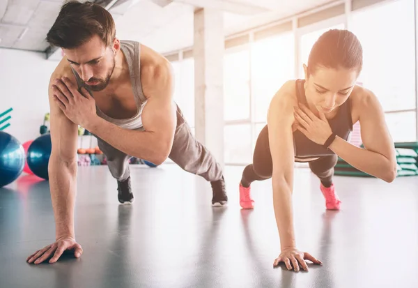 Ragazza magra e uomo forte sono in piedi in una posizione tavola mano e bilanciamento su quella mano. Sembrano concentrati e concisi . — Foto Stock