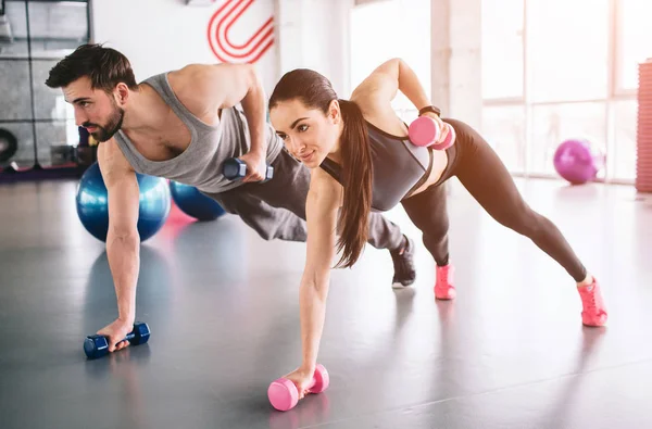 소년과 한 손에 dumbells와 카펫에 서 서 하 고 다른 손으로 뒤 dumbell와 여자의 좋은 사진 — 스톡 사진