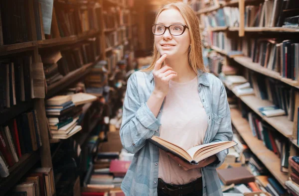 Una persona premurosa e interessante sta pensando a quello che ha letto nel libro che ha. Questa ragazza ha un bel sorriso. . — Foto Stock