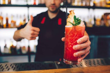Barmen tarafından ayni olduğunu kokteyl bir resim. Güzel kırmızı rengi vardır. Orada da kokteyl ve nane ile kokteyl tübül bir parça üstünde buz.