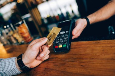 Ödemeler için kullandığı küçük aygıtı kapatın. Sipariş için ödeme kartı herhangi bir türü kullanabilirsiniz. Barmans el ele tutuşarak bir aygıt müşteriler el gold card tutarken.