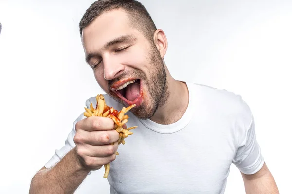 Deze man aanbidt junkfood. Hij houdt heel veel eten. Nu is hij het eten uit zijn handen. Franse frietjes is bedekt met ketchup. Geïsoleerd op witte achtergrond. — Stockfoto