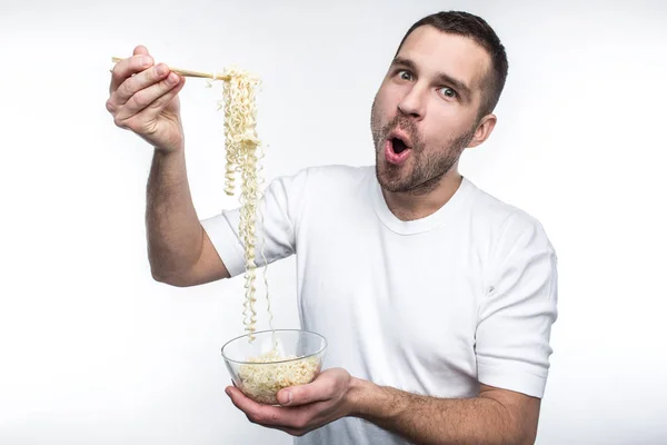 Een beeld van de man die houdt van te eten van de Oosterse keuken. Hij heeft een plaat van Thaise spaghetti en houd het met speciale stokken voor de menselijke voeding. Ook graag dit rare kerel eet junkfood. Geïsoleerd op witte achtergrond — Stockfoto