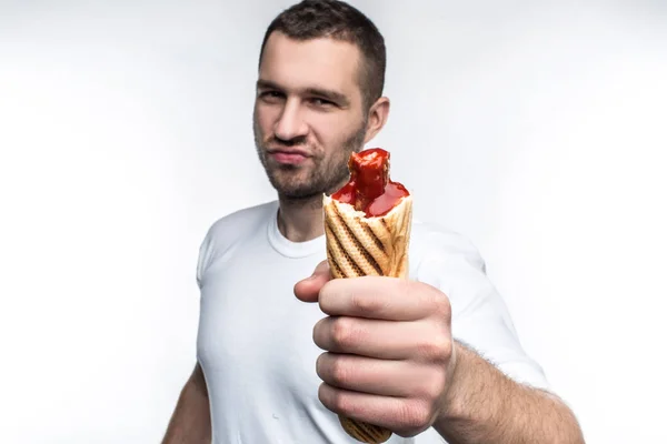 Deze man houdt grote, vette maar smakelijke hotdog. Hij ziet er brutale en ernstige. Hij raden om te eten dit voedsel omdat het is heerlijk. Geïsoleerd op witte backgrond. — Stockfoto