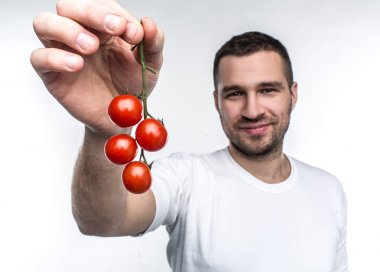Attractive and handsome man is holding a ramus of cherie tomatoes. This vegane likes to eat every fruit and vegetable in a world. He recommends to eat only good food. Isolated on white background. clipart
