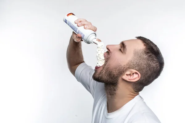 Ele gosta de comida doce entre tudo em um mundo. Este homem está a pôr creme na boca com prazer. Ele não pode parar de o fazer. Isolado sobre fundo branco . — Fotografia de Stock