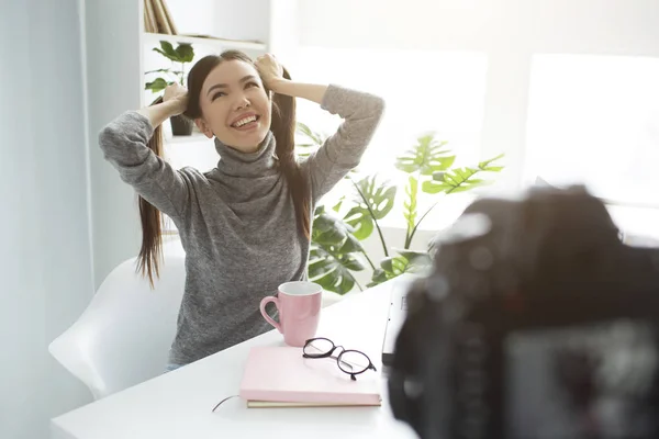 Divertido y feliz blogger está haciendo un nuevo video. Se ha dividido el pelo en dos colas de caballo y se ha reído en voz alta. Ella está disfrutando del proceso de vlogging porque es su hobby . — Foto de Stock