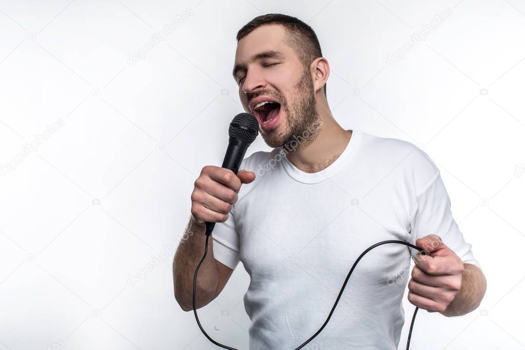 Emotional man is singing song in microphone and rocking out. He is enjoying doing that. Isolated on white background.