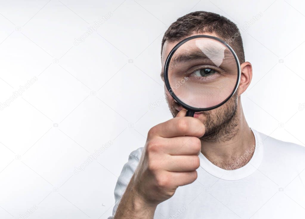 Man with loupe is looking straight ahead and showing his eye through the glass. He is an investigator. Isoolated on white background.