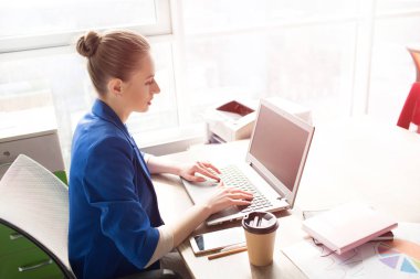 Parlak pencere ve çalışma masasında oturan mavi ceketli iş kadın resim. Klavye üzerinde yazıyor. Wokring internette kızdır.