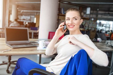 Güzel ve mutlu kadın sandalyede oturan ve konuşuyor. Se kenara arıyorsunuz ve gülümseyerek. Kız biraz dinlenirsem üretken çalışma saatlerinin vardır.