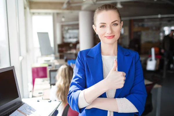 Fin bild på flicka i blå kostym leende. Hon håller ena handen på höfterna och en annan en på jackan. Flickan ser nöjd och glad. — Stockfoto