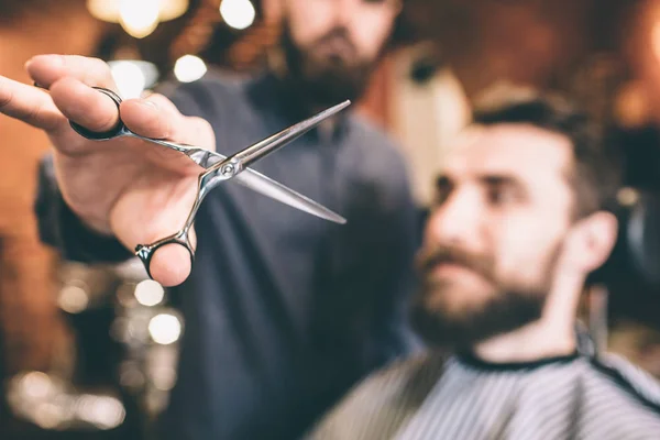 Zbliżenie na nożyczki, który trzyma fryzjerskiego. Nożyczki są otwarte. Klient jest gotowy do procedury. — Zdjęcie stockowe