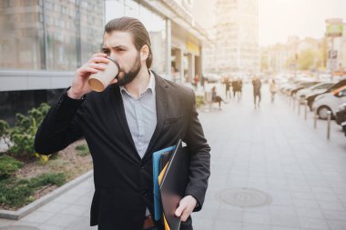 Meşgul bir adam acelesi var, o zaman yok, üstünde belgili tanımlık gitmek telefonda konuşacak. İşadamı arabanın kaputu üzerine birden fazla görev yapıyor. Çoklu görev iş kişi kahve içiyor