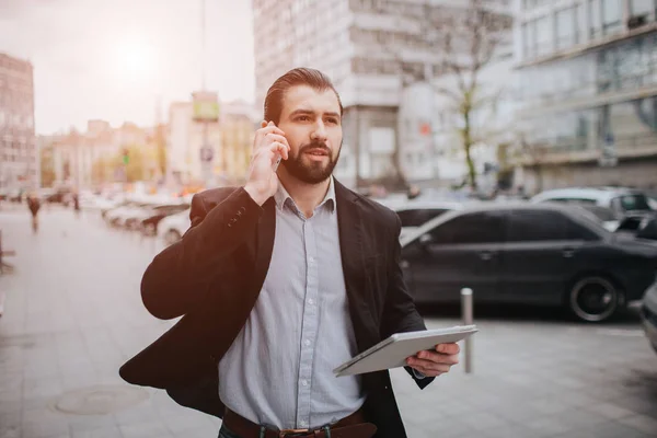 Busy man is in a hurry, he does not have time, he is going to talk on the phone on the go. Businessman doing multiple tasks. Multitasking business person. — Stock Photo, Image