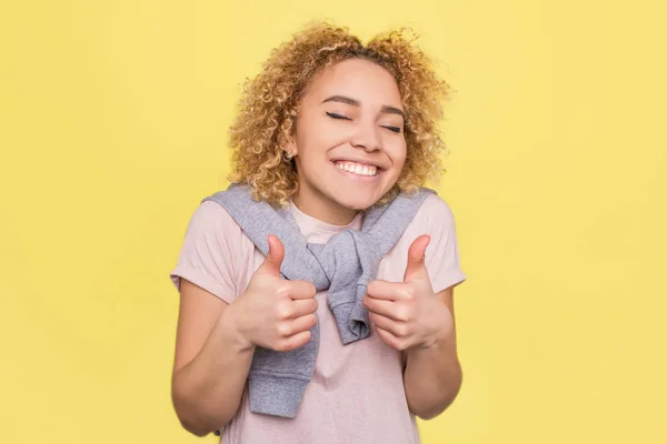 Mädchen lächelt und zeigt große Fingerhüte. Sie ist glücklich. isoliert auf gelbem Hintergrund. — Stockfoto