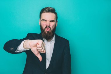 Adam ayakta ve büyük baş parmağını aşağı gösteren. O mutlu ve memnun değil. Bu adam üzülüyor. Üzerinde mavi arka plan izole.