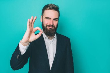 Mutlu bir adam ok sembolü sağ eliyle gösteriyor. Caonfidence ile kameraya bakıyor. Üzerinde mavi arka plan izole.