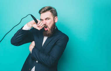 Cool adam şarkı söylüyor. Mikrofon şarkı söylemeyi seviyor. Adam kameraya ciddi bir manzara ile loking olduğunu. Üzerinde mavi arka plan izole.