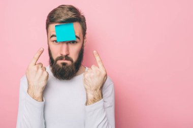 Garip adam bir mavi etiket alnına koydu. O iki elin parmakları ile işaret ediyor. Pembe arka plan izole.